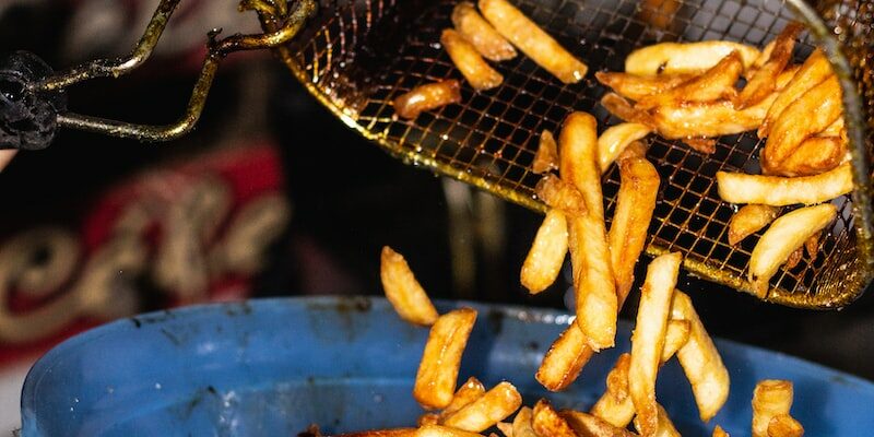 person transferring fries from basket to a bowl