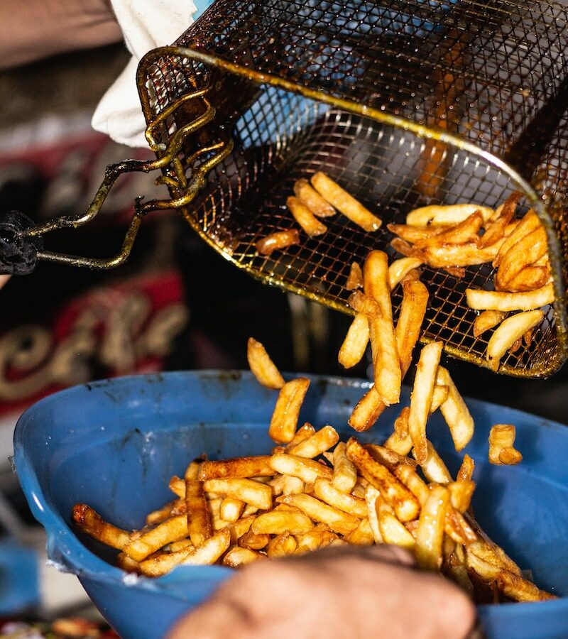 person transferring fries from basket to a bowl